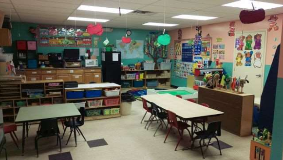 Preschool classroom with tables, bulletin boards, and educational decorations