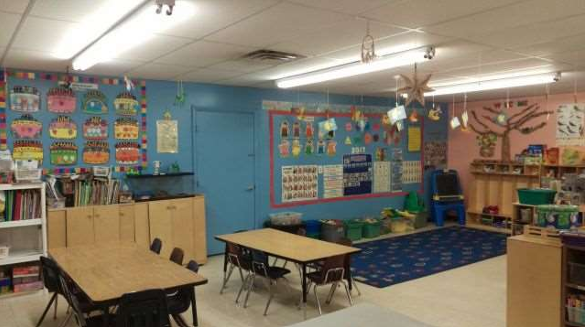 School-age classroom with group tables, rugs, and learning materials